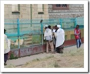 The guy behind the blue fence is the guardian of the Ark of the Covenant kept in the building behind him.